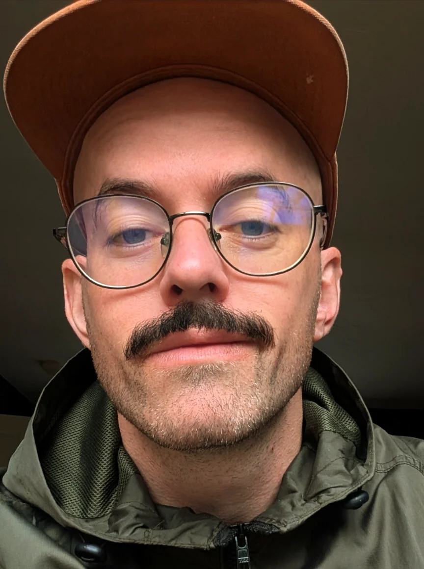 John Bell, in glasses and a tan cap